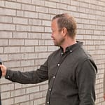 man and woman inspecting there ev charger by ease installed on brick wall